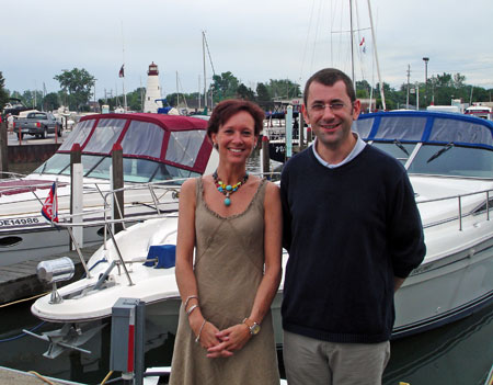 Marianne Poumay and François Georges stand on a dock with boats in the background.