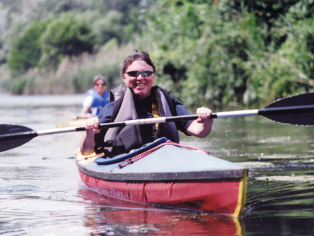 Mark Schofield sitting in kayak holding paddle. Marie-Jeanne Monette paddles in a kayak behind him.