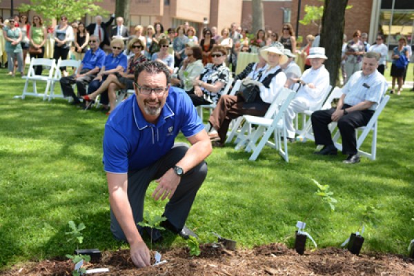 Alumni association president Mike Bates plants a tree seedling