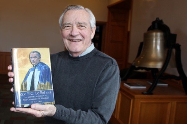 Historian George McMahon poses with a copy of his latest book in the lobby of Assumption University.