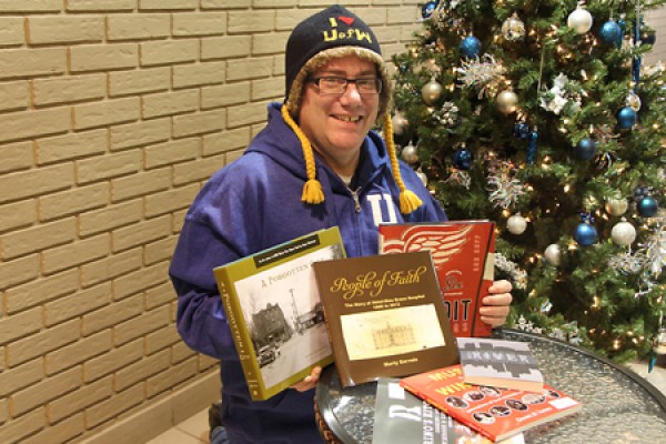 Martin Deck holding books in front of Xmas tree