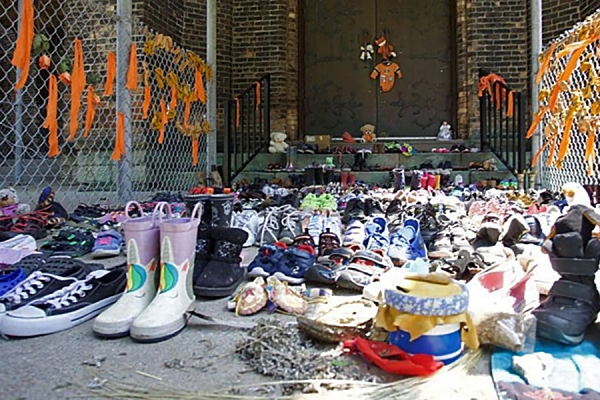 shoes placed outside entrance to Assumption Church, symbolizing children who died in residential schools