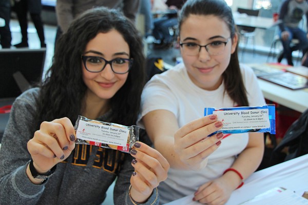 Desiree Mikhael and Milana Milivojevic, volunteers with the UWin Blood Club, display packets of cookies.
