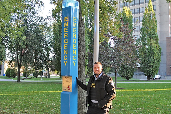 officer standing before emergency blue light pole