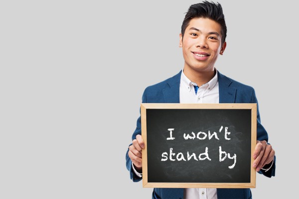 man holding sign reading &quot;I won&#039;t stand by.&quot;