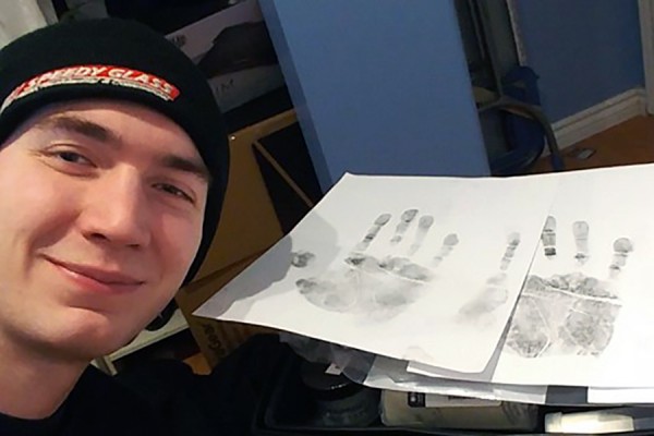 young man posing next to inked handprints