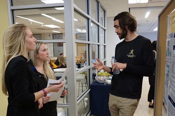 Grad student Kieran Hawksley describes his research project to two students.