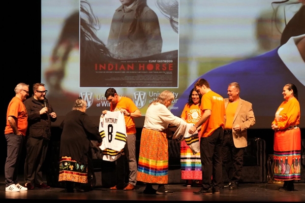 Indigenous Knowledge Keepers, administrators, and student-athletes on the stage