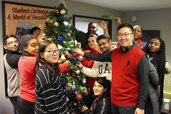 Students from around the world hang ornaments on a tree