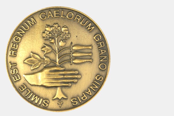 the Christian Culture Gold Medal depicts a human hand holding a mustard plant with the Latin inscription “the kingdom of heaven is like a mustard seed.”