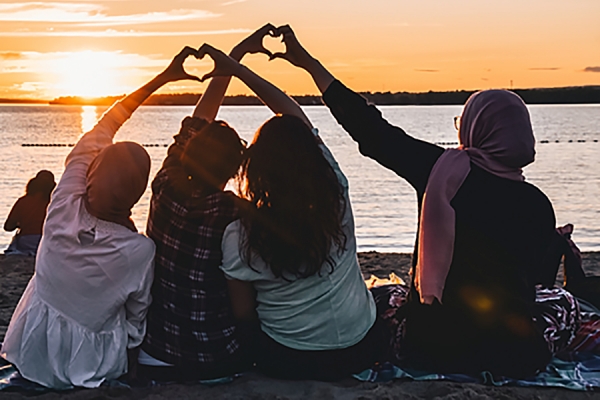 young people sitting on beach at sunrise