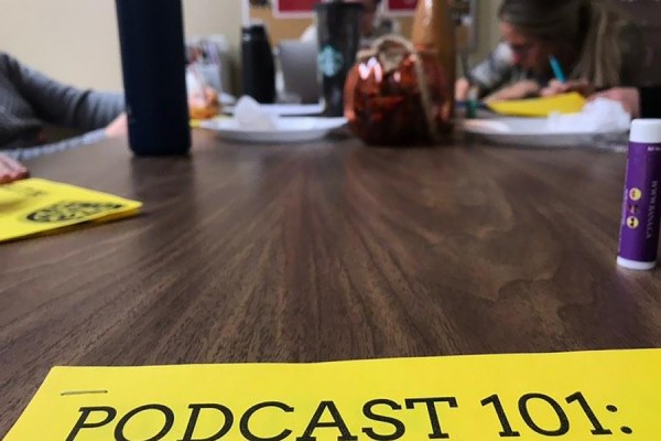 Group working behind sign that reads &quot;Podcast 101&quot;