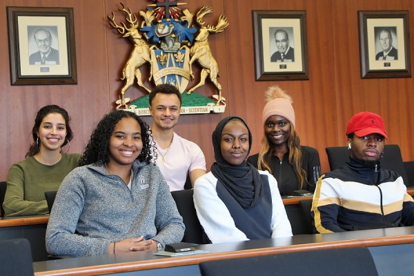 in the Senate chambers: Lena Sleiman, Crystal Bryan, Brayden Butler, Idil Mahamud, Achol Bab, Peter Ndubu.