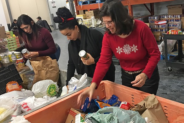 Selena Chauhan, Nour Hachem, and Linda DiPaolo sort donations to the Unemployed Help Centre as part of a community service learning experience.