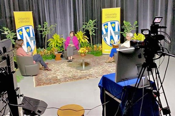 Video cameras frame a panel discussion.