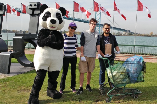 Students and a panda mascot pose with bags of litter.