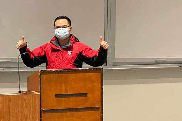masked instructor speaking from podium