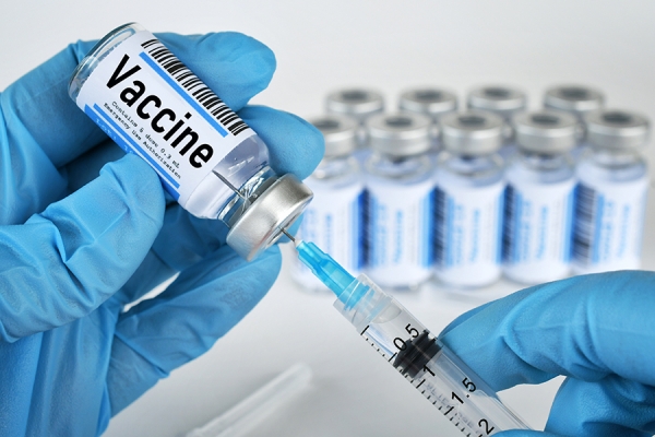 syringe entering vial of vaccine