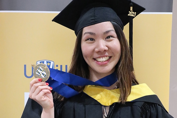 Anita Hu in graduation gown holding medallion