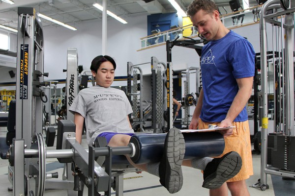 Fit Together participant Nicolas Tran builds up his leg strength under the watchful eye of volunteer trainer Tyler Snyder.