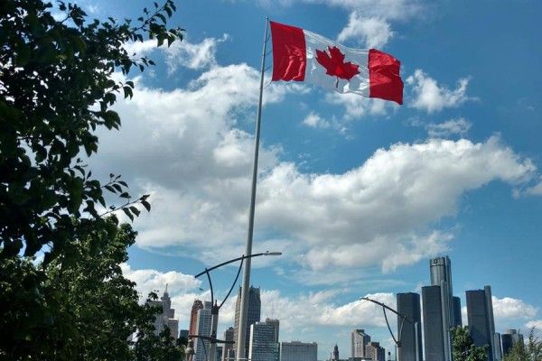 Canadian flag flying against Detroit skyline
