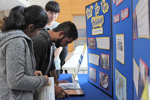 Lok Liu helps Bhagya Sri Pepakayala and Abhishek Mothukuru register for the Host for the Holidays program.