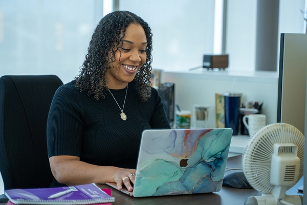 young woman smiles while working on computer