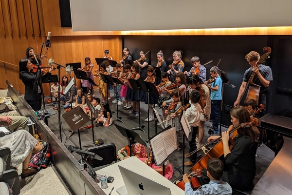 Young musicians perform in orchestra pit.