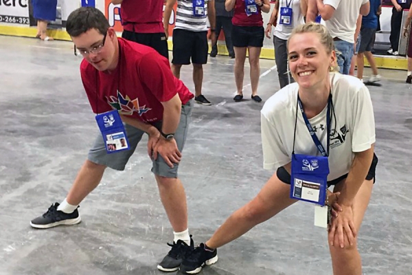 Sarah Hébert (right) leads a competitor through warm-up stretches in preparation for the Special Olympics.