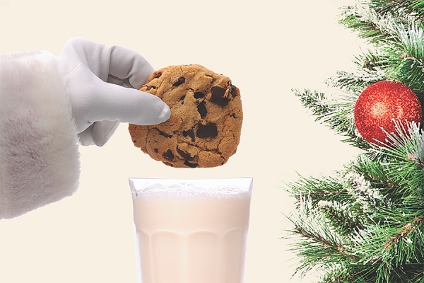 gloved hand holding cookie over glass of milk