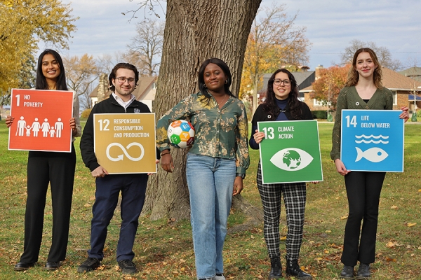 students hold signs listing United Nations sustainability goals