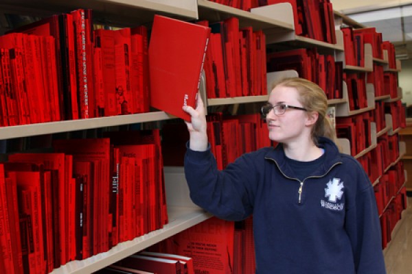 student Melanie Grondin pulls a book from a shelf