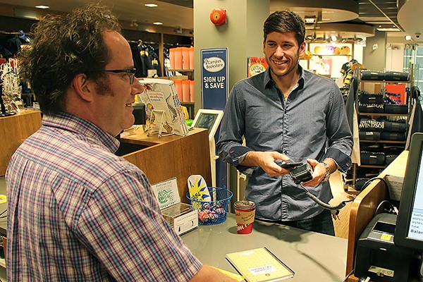 Martin Deck of the Campus Bookstore rings through a purchase for student Chris Easby, using his iPhone to pay for it.