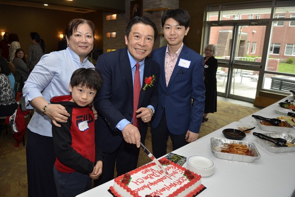 Ben Kuo cuts into a cake with his wife and two sons