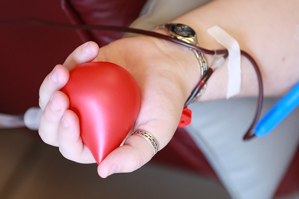 hand of blood donor holding red drop-shaped squeeze toy