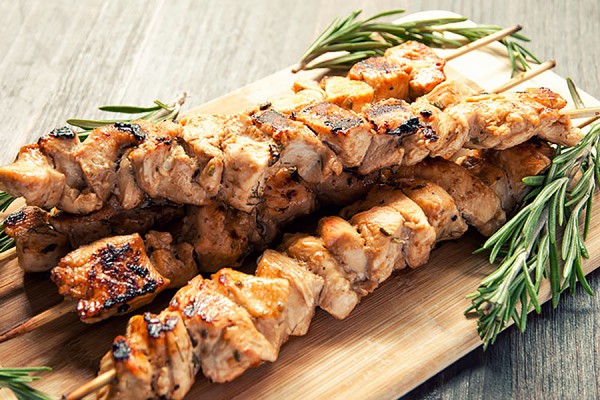 Skewers of grilled chicken souvlaki garnished with rosemary sprigs