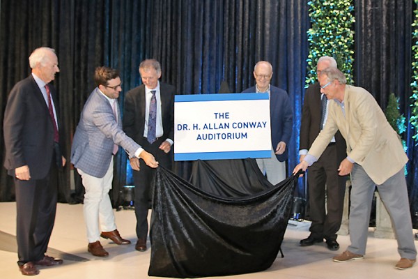 Allan Conway looks on as UWindsor officials and members of the Odette family unveil a plaque signifying the naming of a lecture hall in his honour.