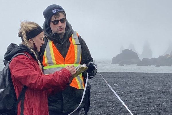 two students compare notes on a measurement on a beach in Iceland