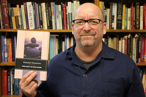 Jeff Noonan holding copy of Embodied Humanism