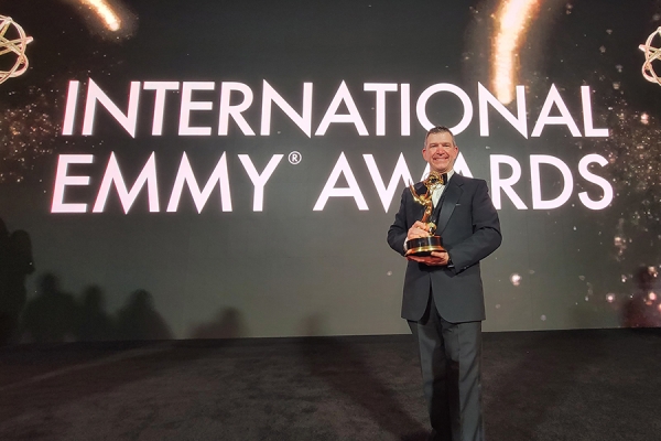 Stephen Paniccia holding Emmy statuette on gala stage
