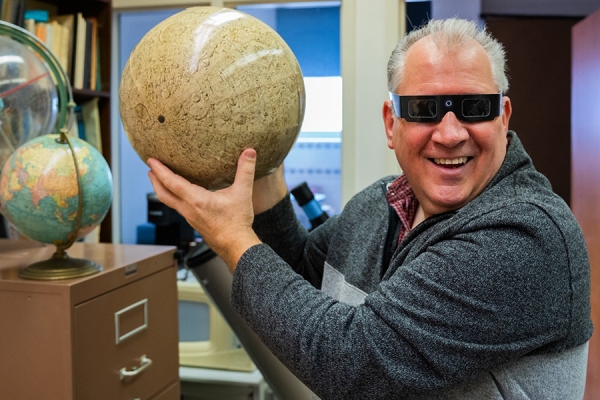 Astronomer Steve Pellarin holding lunar globe