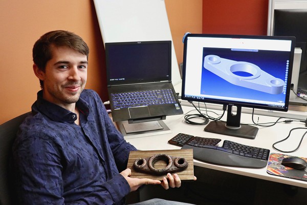 Shane Peelar, a doctoral student of computer science, displays a sample machine part created by three-dimensional printing.