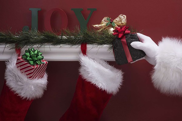 Hand placing gift in stocking hung on fireplace