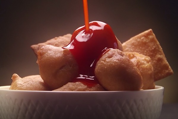 Chicken balls being covered in sweet-and-sour sauce