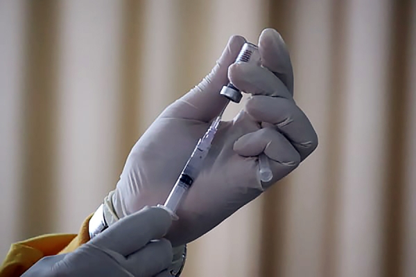 hand holding vial of vaccine