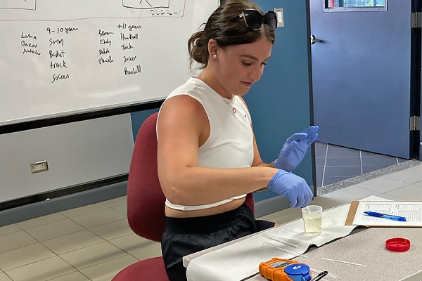 Vanessa Pidutti taking measurements of vial of yellow liquid