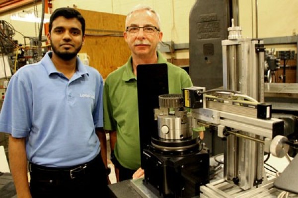 Shanawaz Ali Mohammad and Ken Bishop stand with the laser-based custom measuring machine