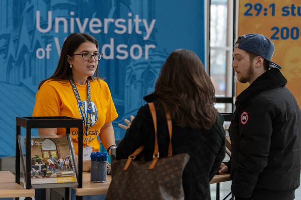 Student helping visitors register for open house