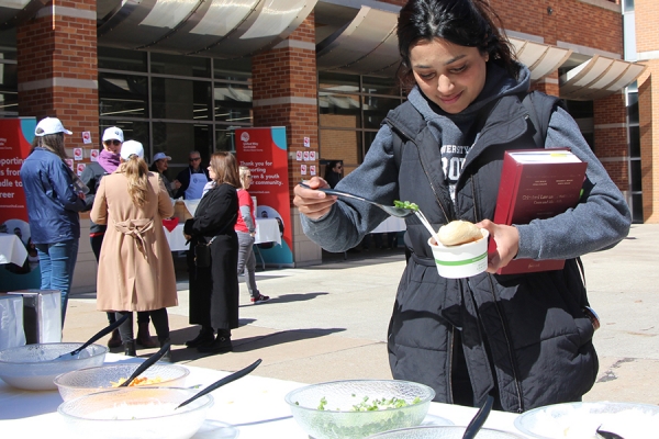 Asiah Sadiq spoons green onions atop a bowl of chil