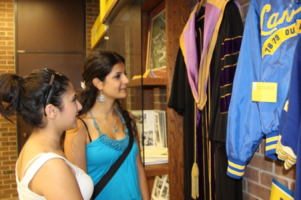 A graduation gown and a varsity jacket are among the artifacts viewed by first-year students Shahad Bahi and Mariam Shamoun.